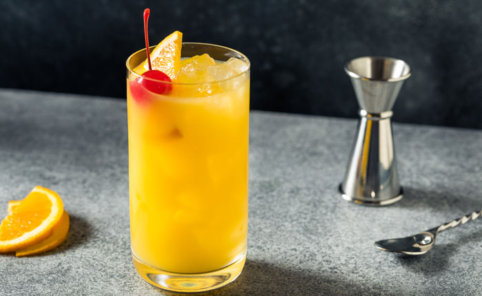 Glas auf einem Tisch, welches den Harvey Wallbanger Cocktail beinhaltet