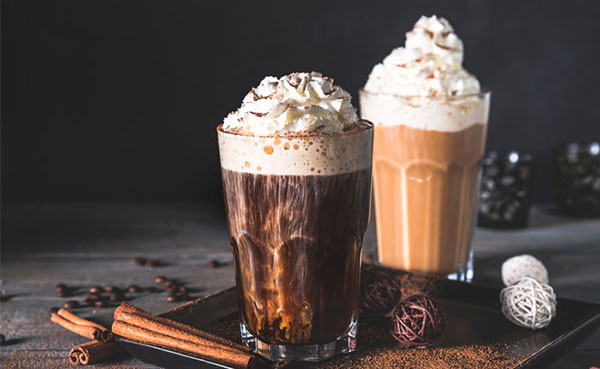 zwei Gläser mit unterschiedlich dunklem Kaffee, Likör, Sahnehaube